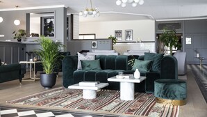 Una sala moderna con un sofá verde oscuro, una mesa de centro y una planta grande en maceta.