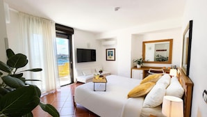 A hotel room with a bed, a desk, a chair, a TV, a balcony with a view, and a plant. - Best Western Hotel Martello (Lampedusa)
