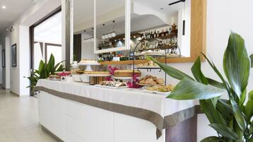 A buffet setup with various food items, a mirror reflecting the room, and a bar area with bottles.