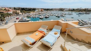A balcony with two sunbeds overlooking a marina with boats. - Best Western Hotel Martello (Lampedusa)
