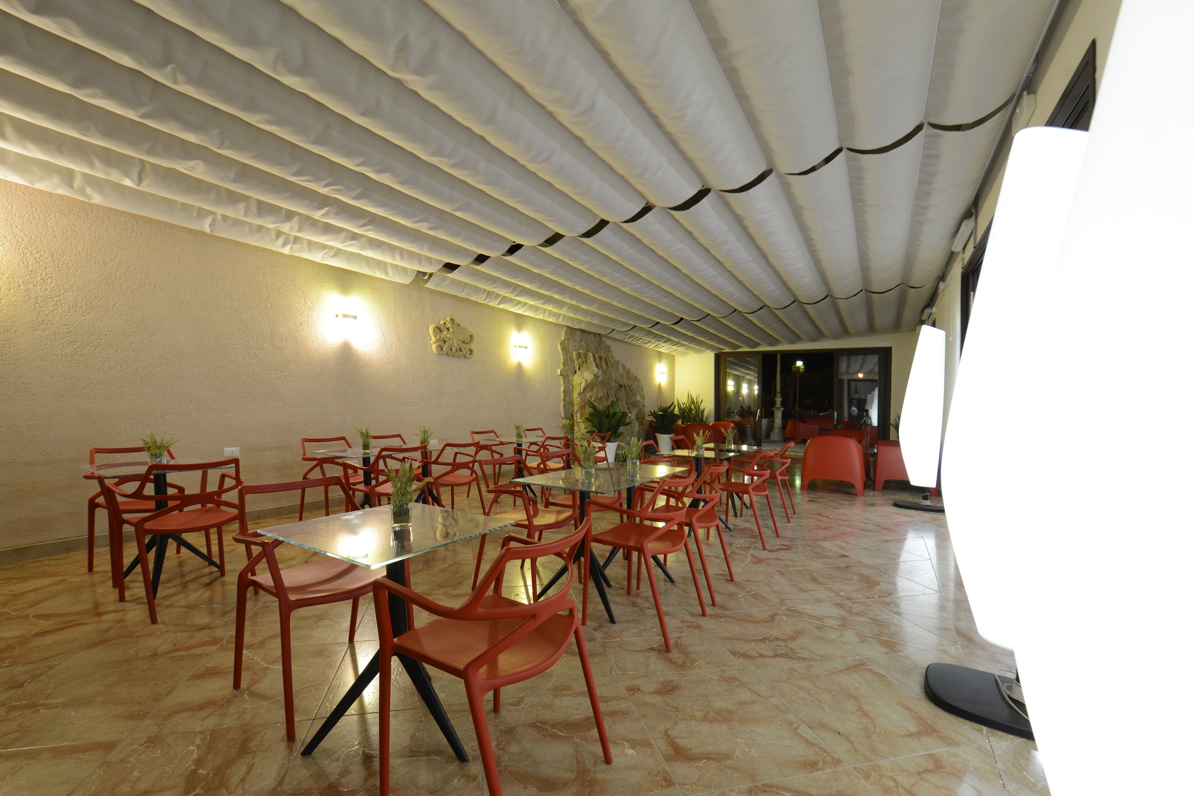 A conference room with a glass table, red chairs, and a tiled floor.