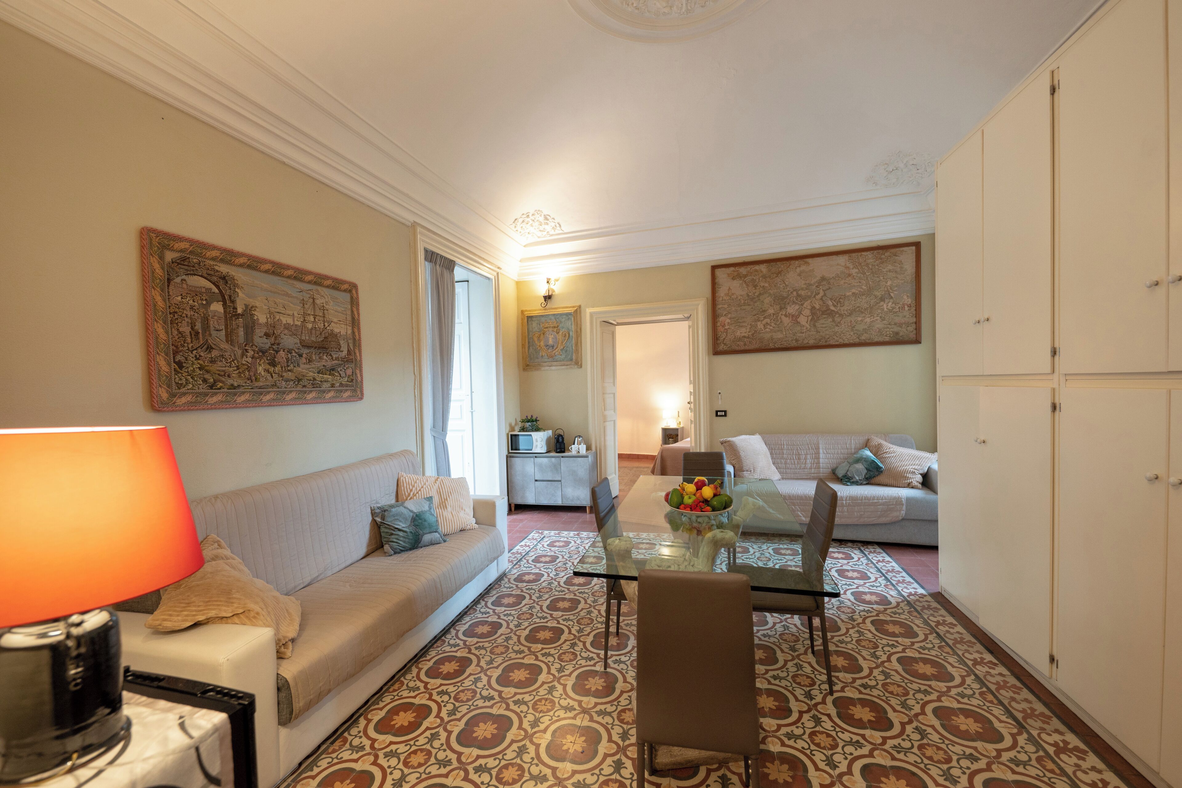 Un salon comprenant un canapé, une table à manger avec des chaises, une lampe et un tapis à motifs.