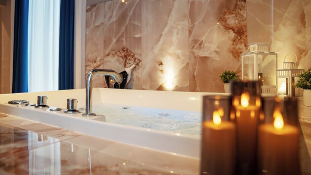 Un baño moderno con una bañera grande, una pared de mármol y una pequeña planta en maceta.