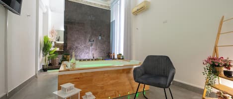 Moderni huone, jossa on puinen vastaanottotiski, biljardipöytä, harmaa tuoli ja puinen hylly, jossa on kasveja.