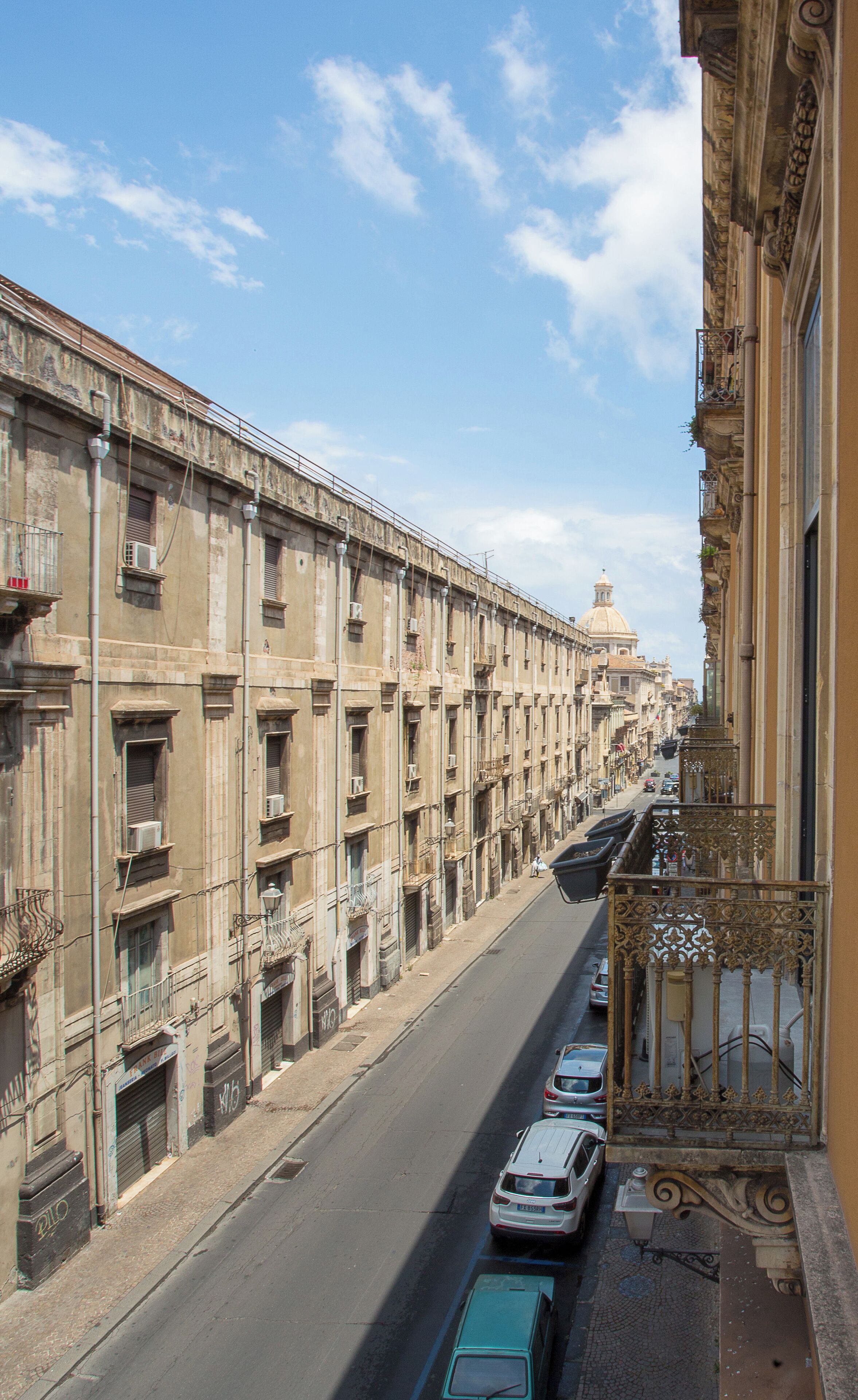Vista de una calle con una hilera de edificios históricos, cielo despejado y automóviles estacionados.
