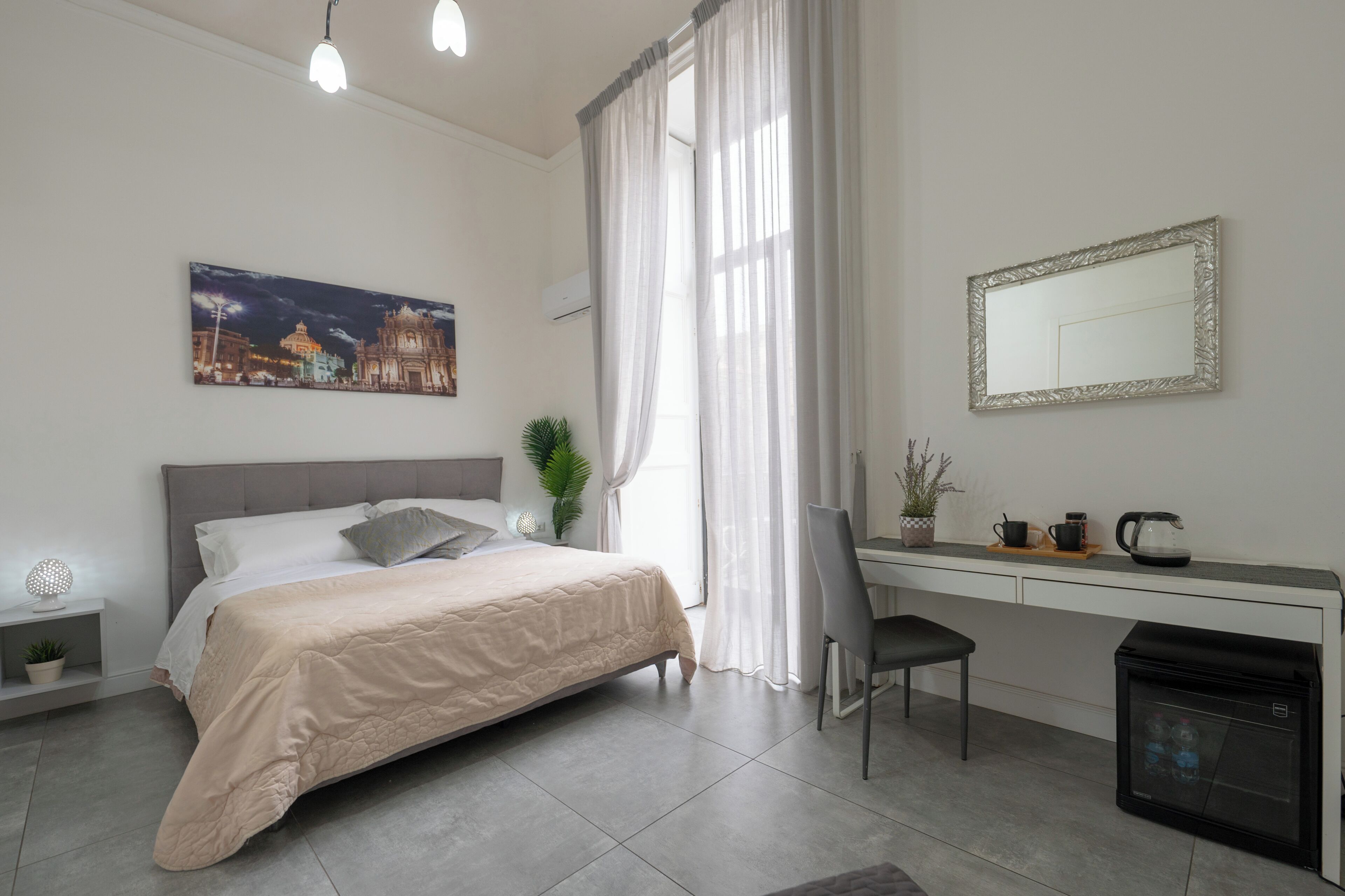 Een slaapkamer met een bed, nachtkastje, stoel, bureau en een kleine koelkast.