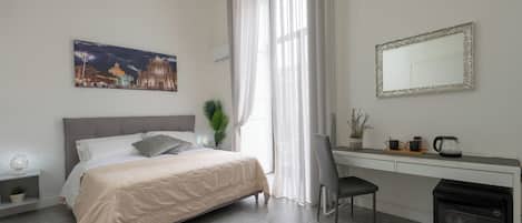 A bedroom with a bed, bedside table, chair, desk, and a small refrigerator.