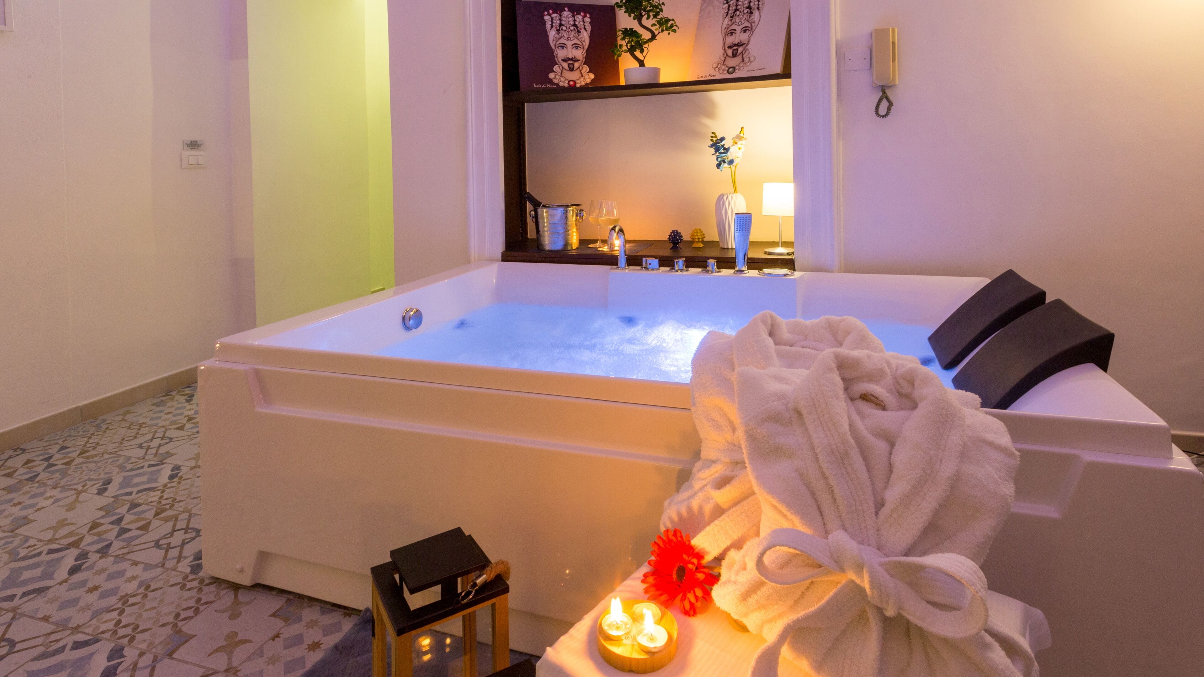 Une salle de spa équipée d’une baignoire, d’une serviette, de bougies et d’une petite table sur laquelle est posé un livre.