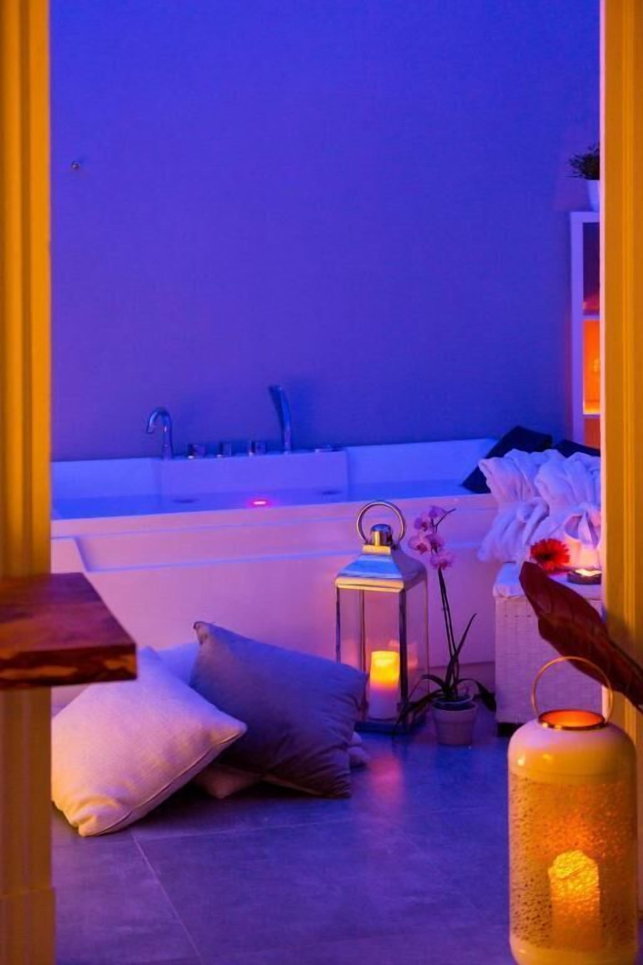 Une salle de spa équipée d’une baignoire, de coussins, d’une petite table et d’une lanterne.