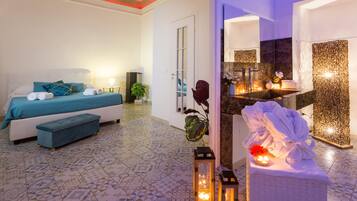 A modern hotel room with a bed, bedside table, and a bathroom with a sink and mirror.