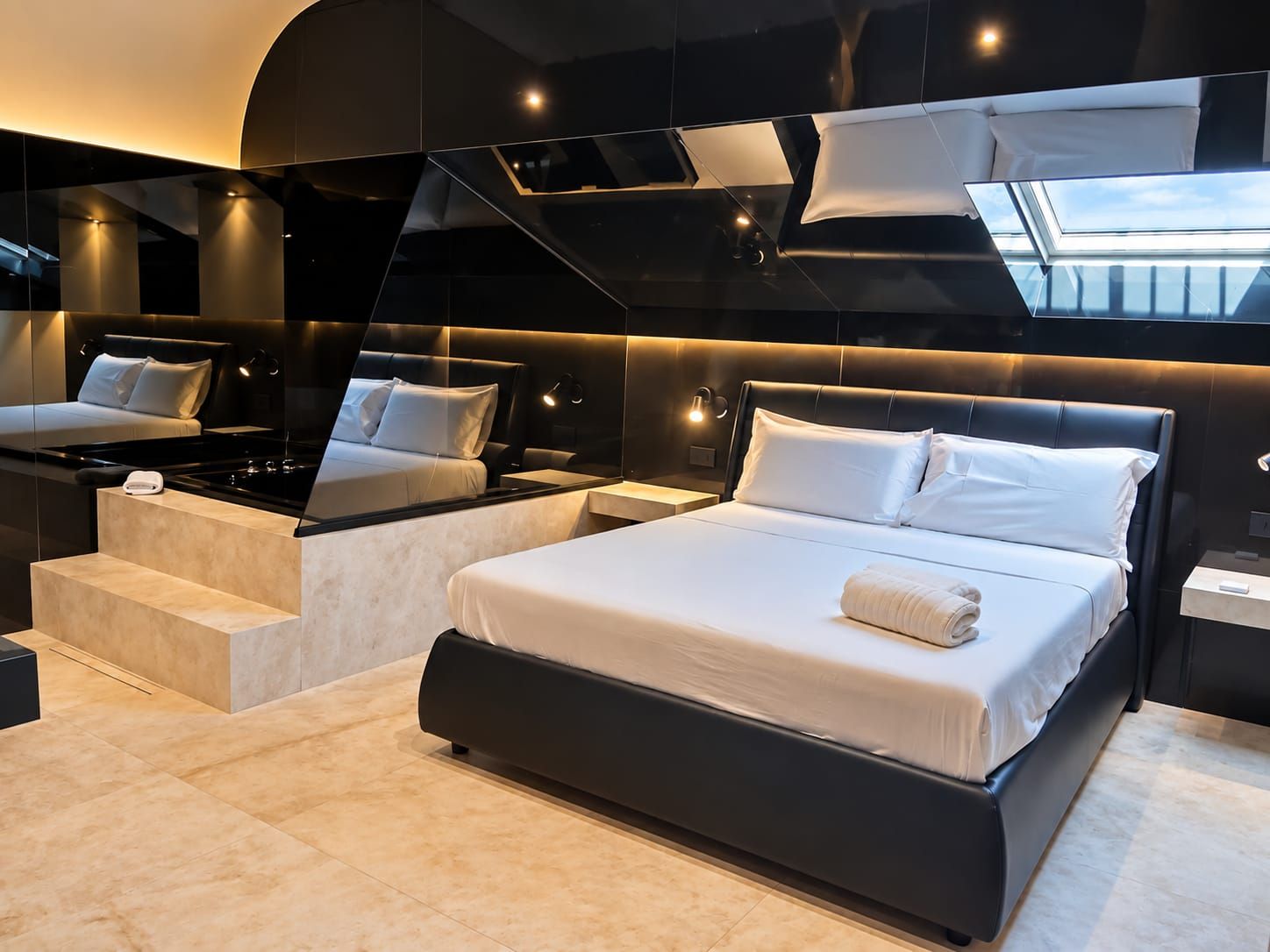 Une chambre d’hôtel moderne dotée d’un grand lit, d’un coin salon séparé et d’une lucarne.