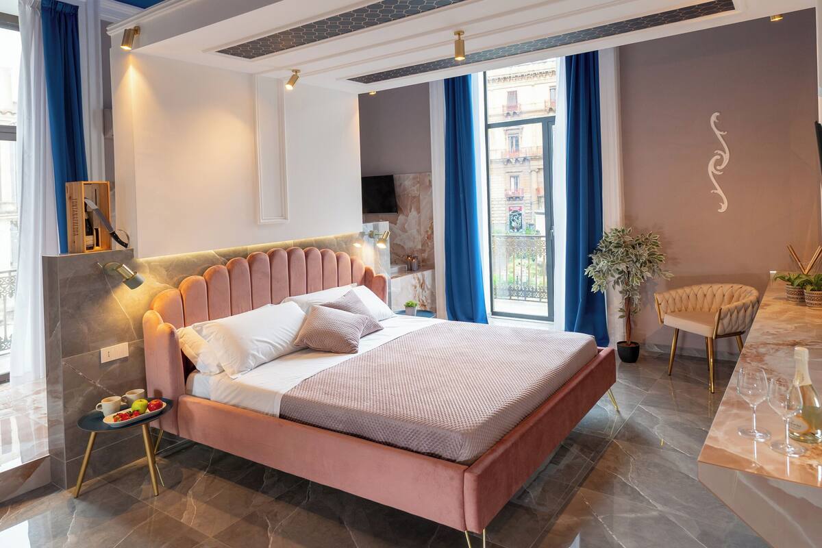 A modern bedroom with a large bed, a ceiling medallion, and a view of the city.