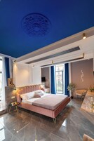 A modern bedroom with a large bed, a ceiling medallion, and a view of the city.