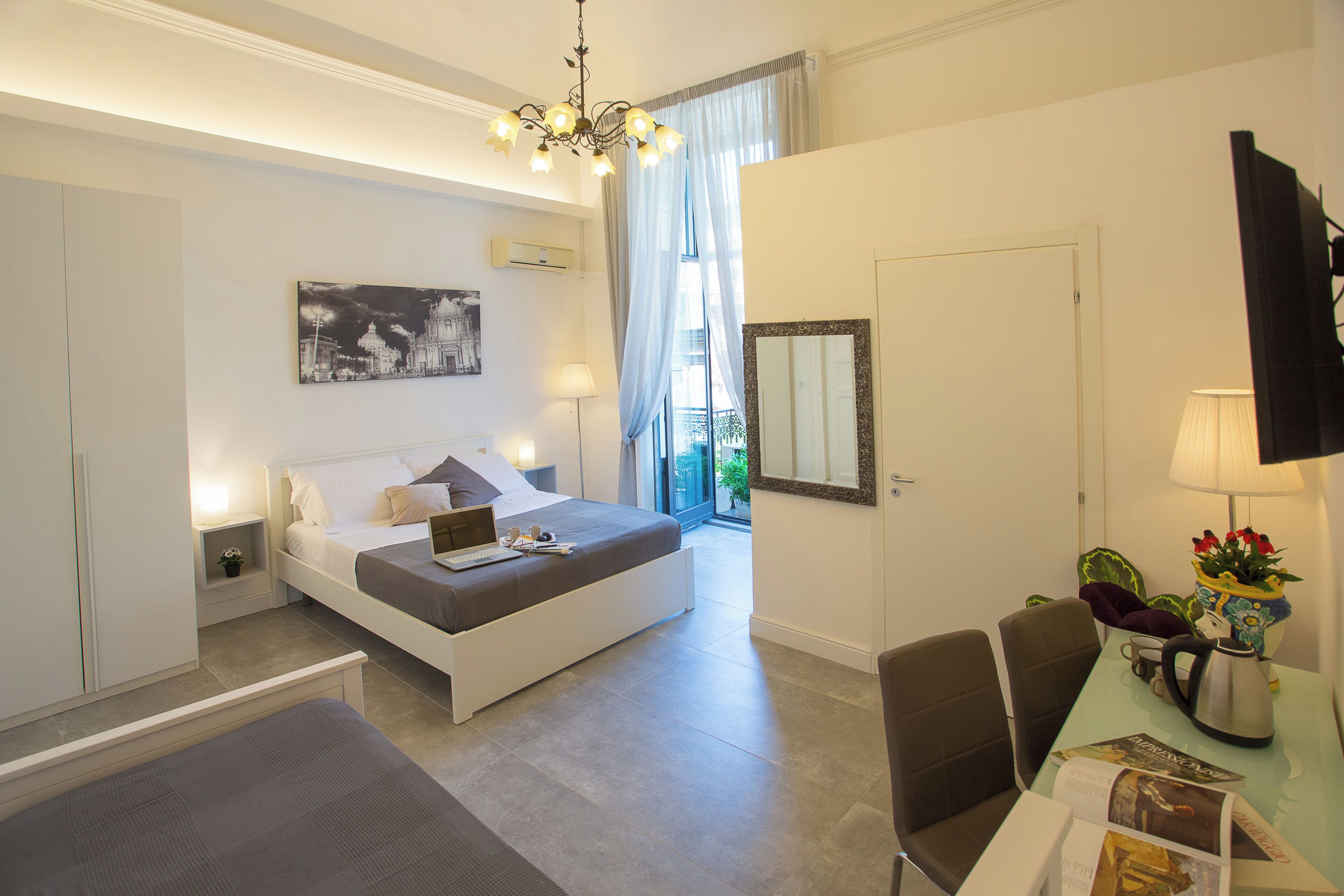 A modern bedroom with a bed, bedside table, lamp, and a view of the outdoors.