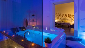 Un baño moderno con una bañera grande, una zona de ducha con mampara de cristal y una planta en maceta.