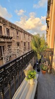 Un balcone con ringhiera in ferro battuto, una panchina e piante in vaso.