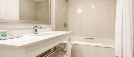 Un baño moderno con lavamanos, espejo y ducha blancos.
