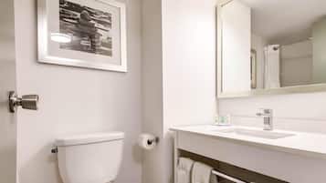 A bathroom with a toilet, a framed picture on the wall, a sink with a mirror, and a towel rack.