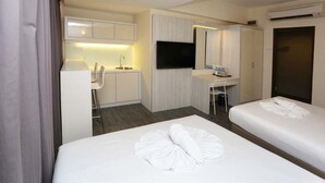A hotel room with two beds, a desk, a chair, a TV, and a wardrobe. - Hotel Westree (Kuala Lumpur)