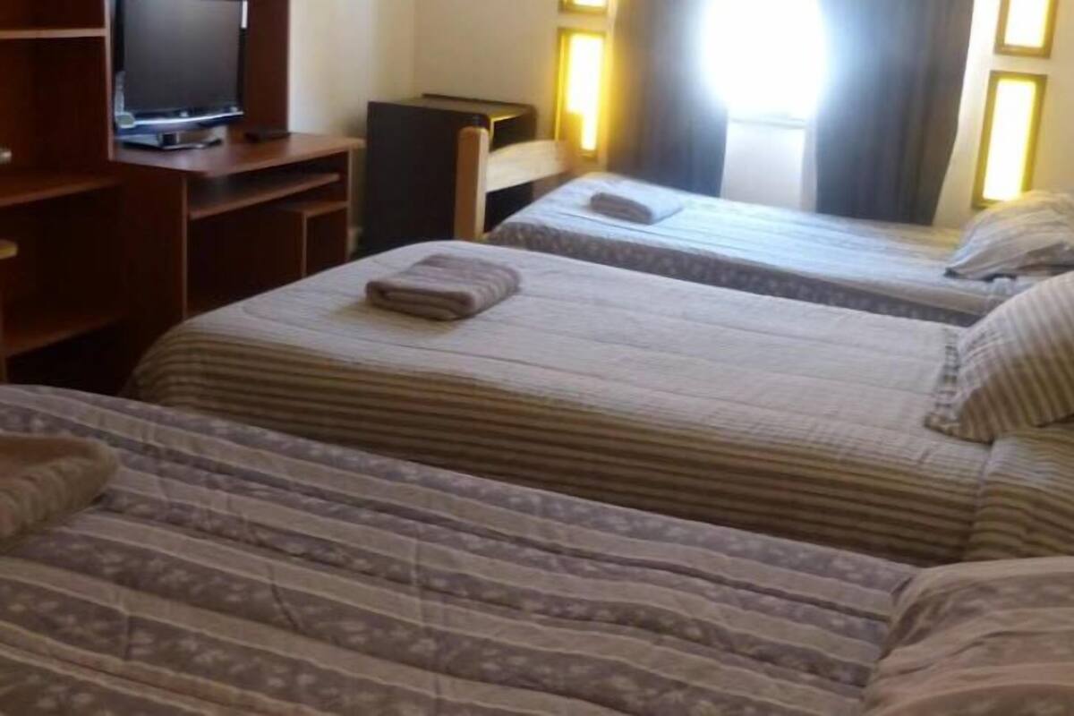 A hotel room with two beds, a television, and a desk.