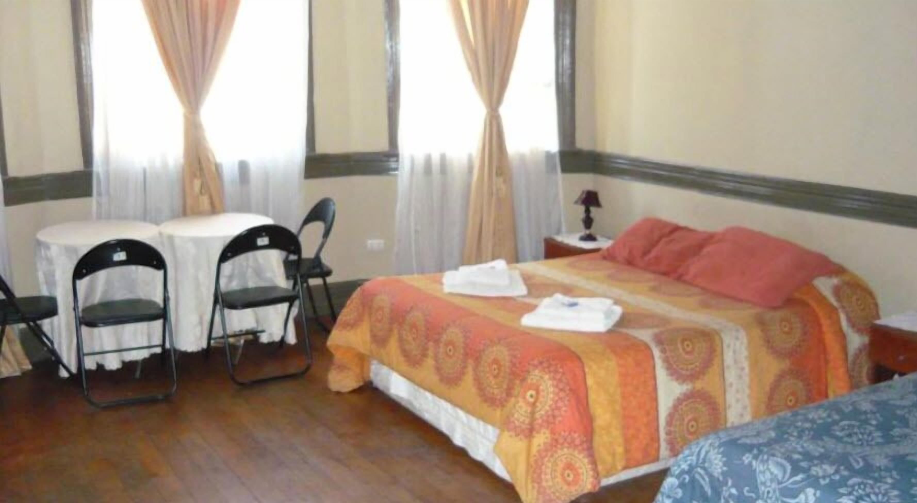 Una habitación de hotel con una cama, dos sillas, una mesita y una mesita de noche.