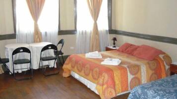 Una habitación de hotel con una cama, dos sillas, una mesita y una mesita de noche.