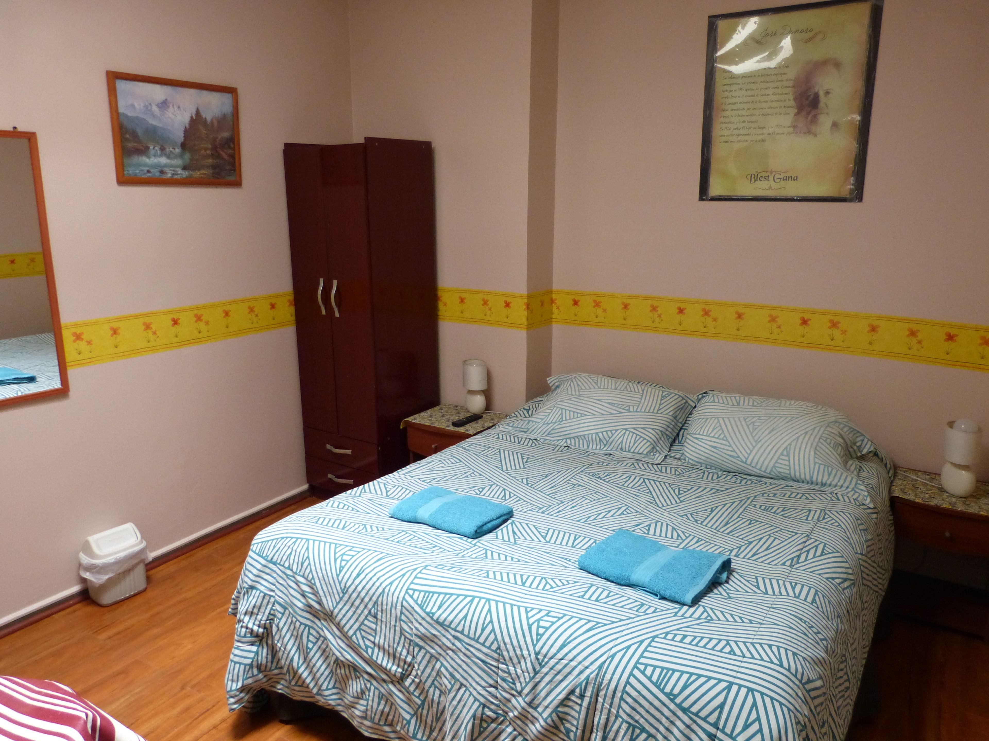 Un dormitorio con cama, armario, mesita de noche, espejo y un cuadro en la pared.