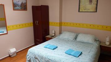 Un dormitorio con cama, armario, mesita de noche, espejo y un cuadro en la pared.