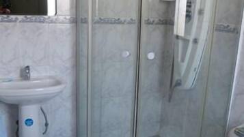 Un baño con ducha de vidrio, lavamanos y retrete.