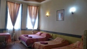 A hotel room with two single beds, a small table, and a chair.