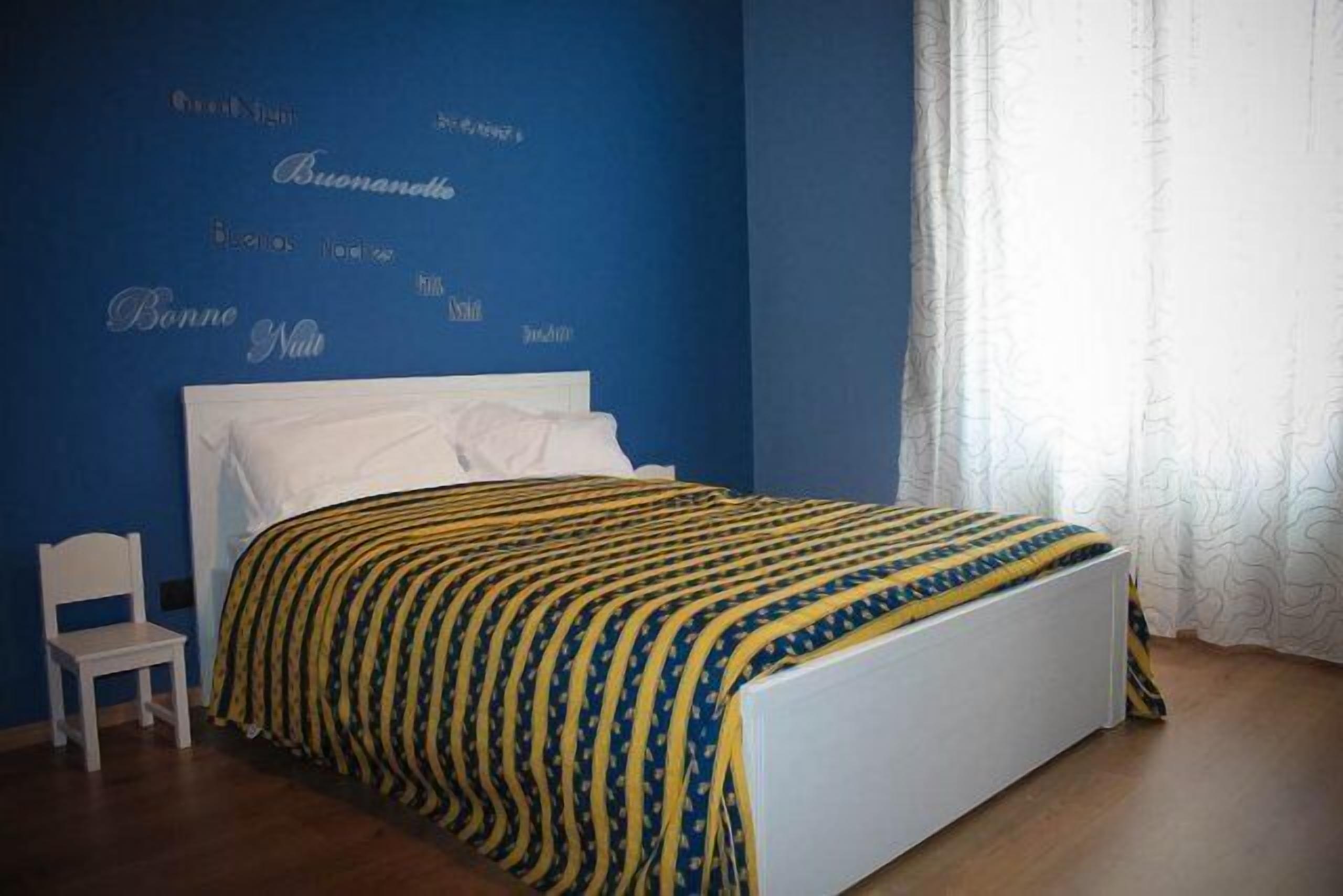 A bedroom with a bed, a chair, and a wall with text.