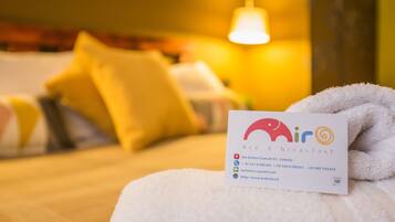 Una habitación de hotel con una cama, una toalla blanca y una tarjeta de presentación sobre la cama.