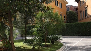 A residential street with a row of yellow buildings, a well-maintained lawn, and a hedge along the sidewalk. - Roma Room Hotel (Rome)