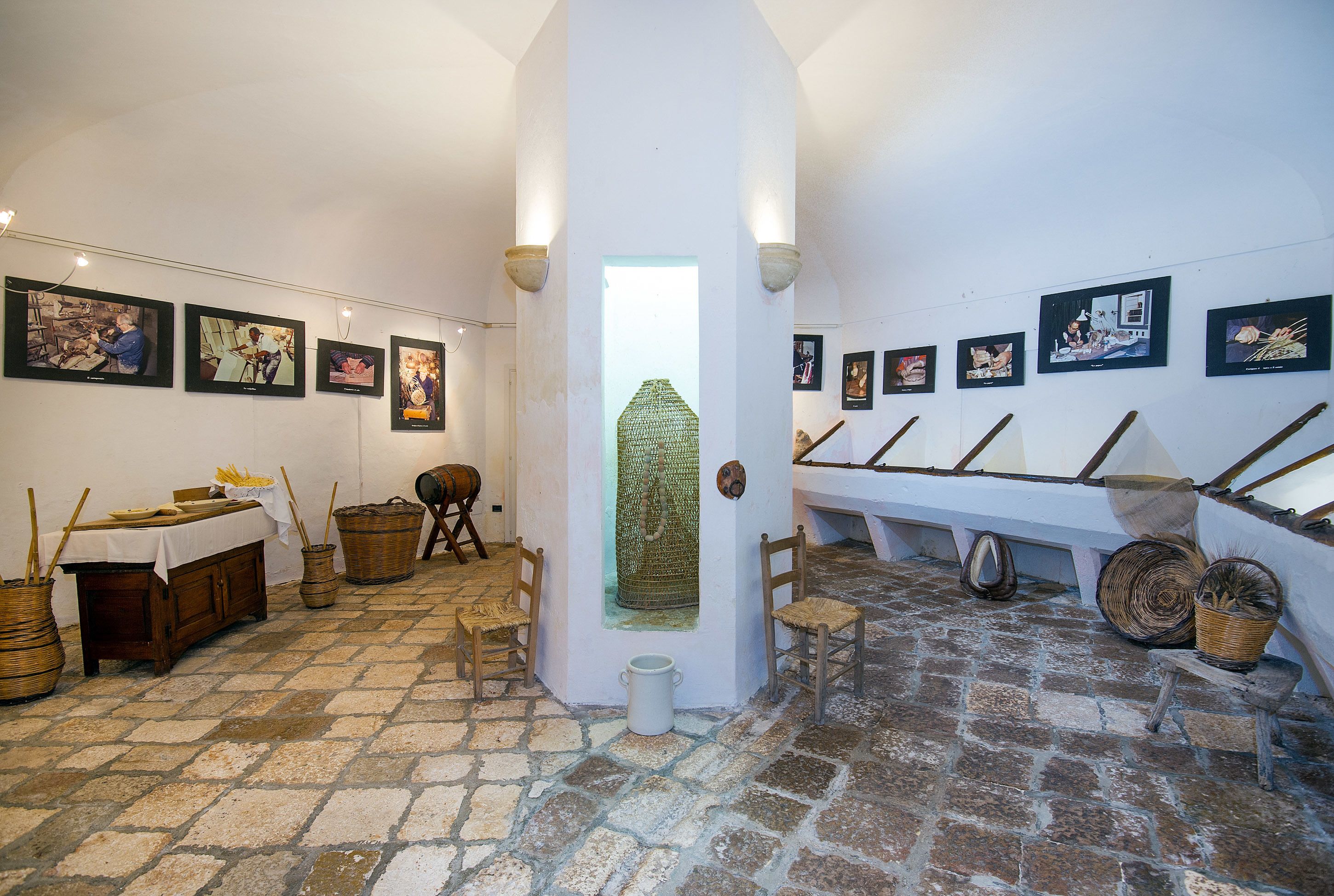 Un interior rústico con suelo de piedra, mobiliario de madera y obras de arte enmarcadas en las paredes.