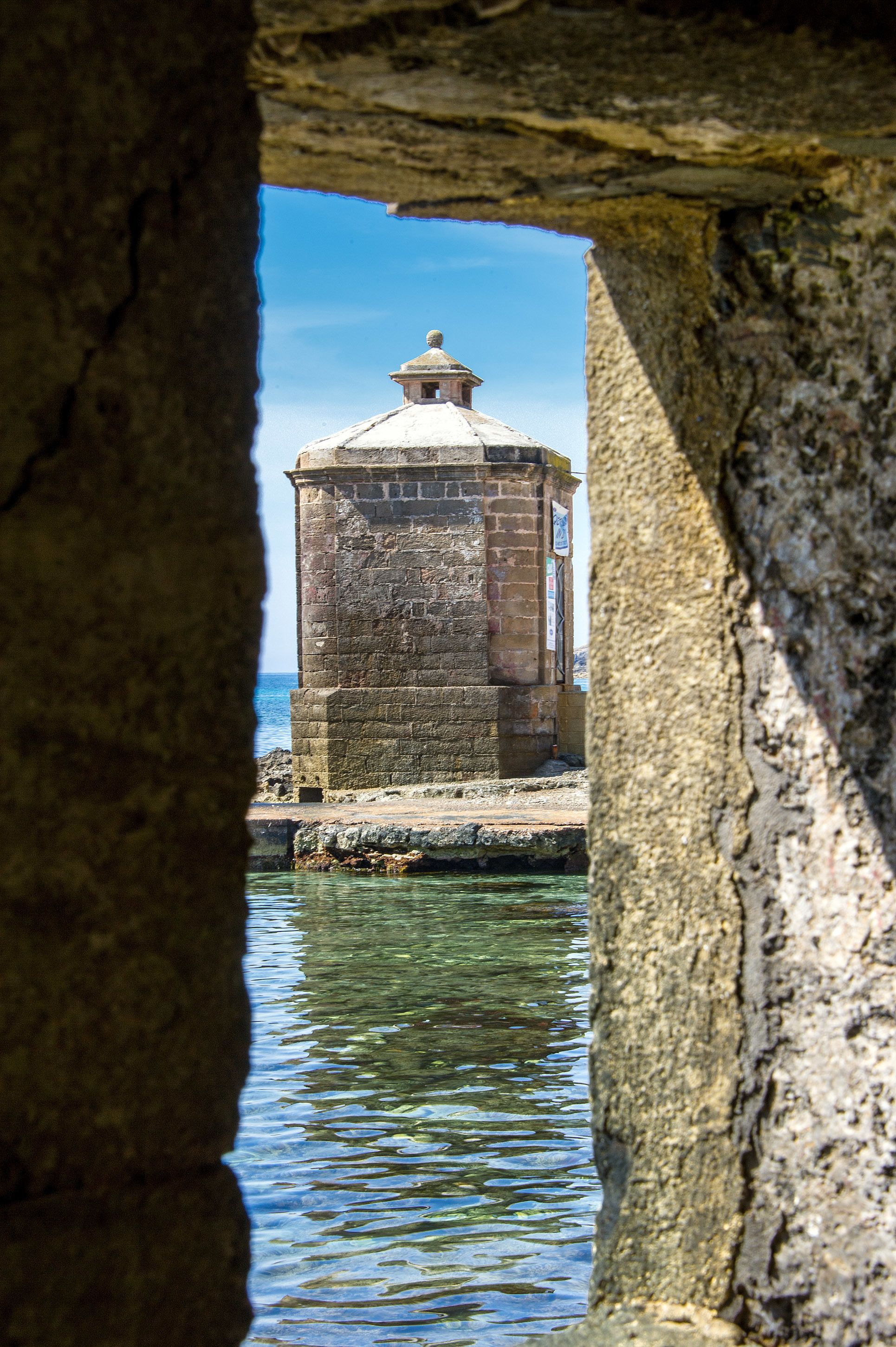 A stone structure with a domed roof overlooking water.