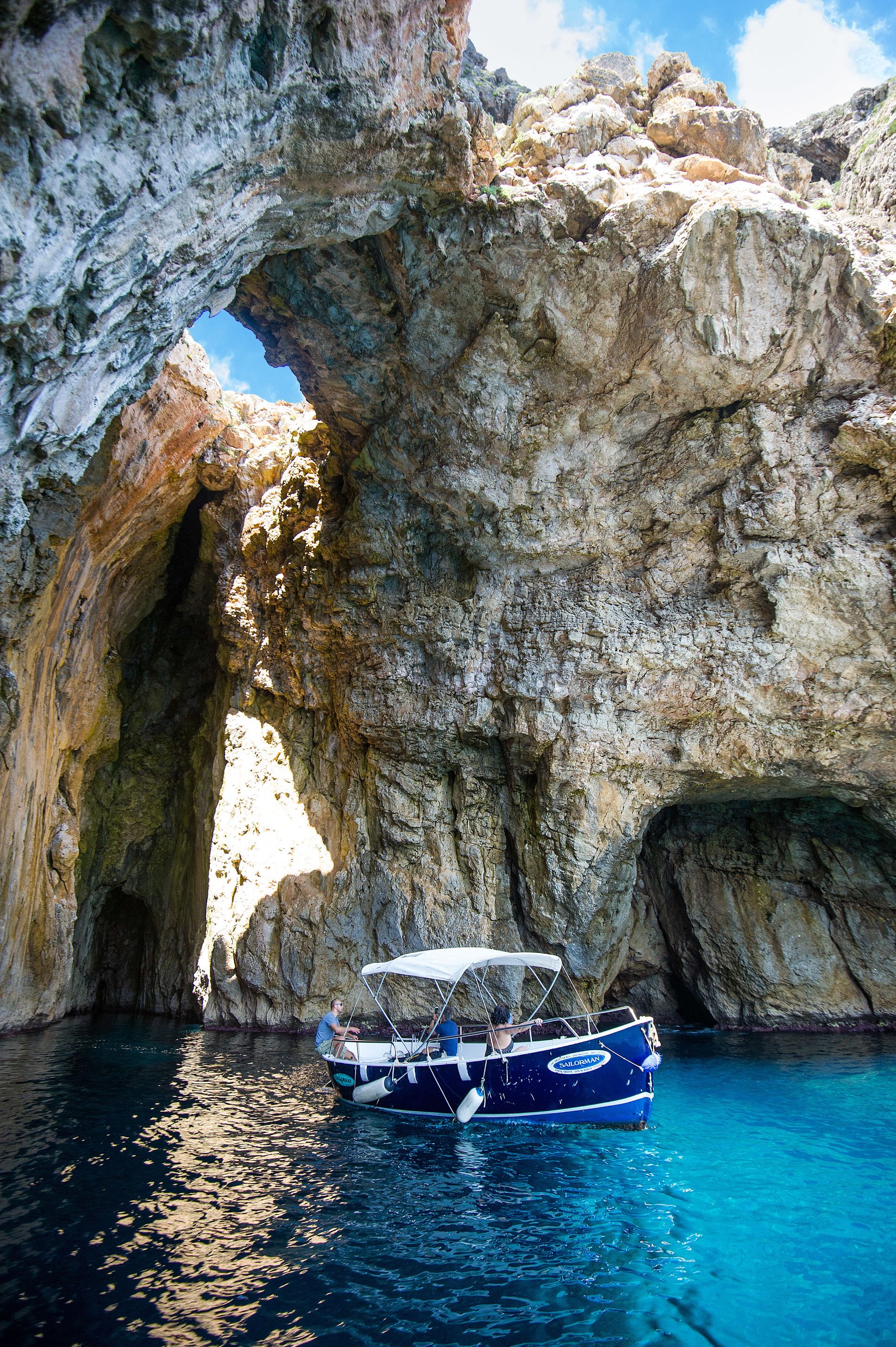 Un bote anclado cerca de una formación rocosa natural con una abertura similar a una cueva.