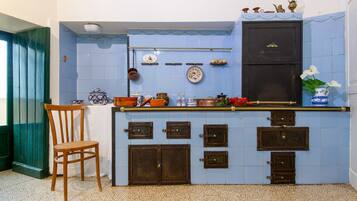 A kitchen with blue tiles, wooden cabinets, and a chair.