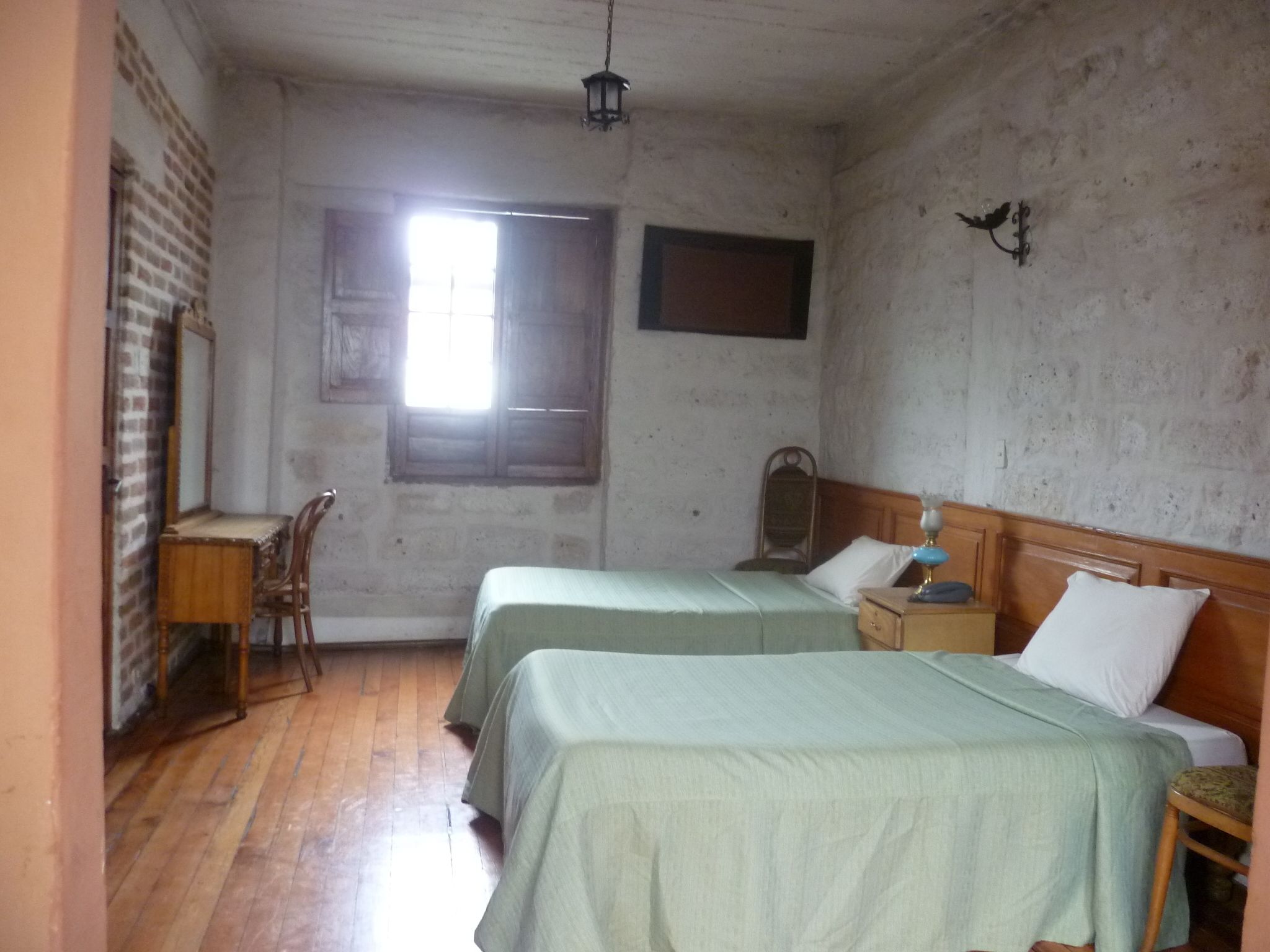 Una habitación con dos camas, un escritorio y una ventana.