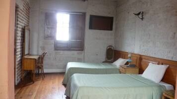 Una habitación con dos camas, un escritorio y una ventana.