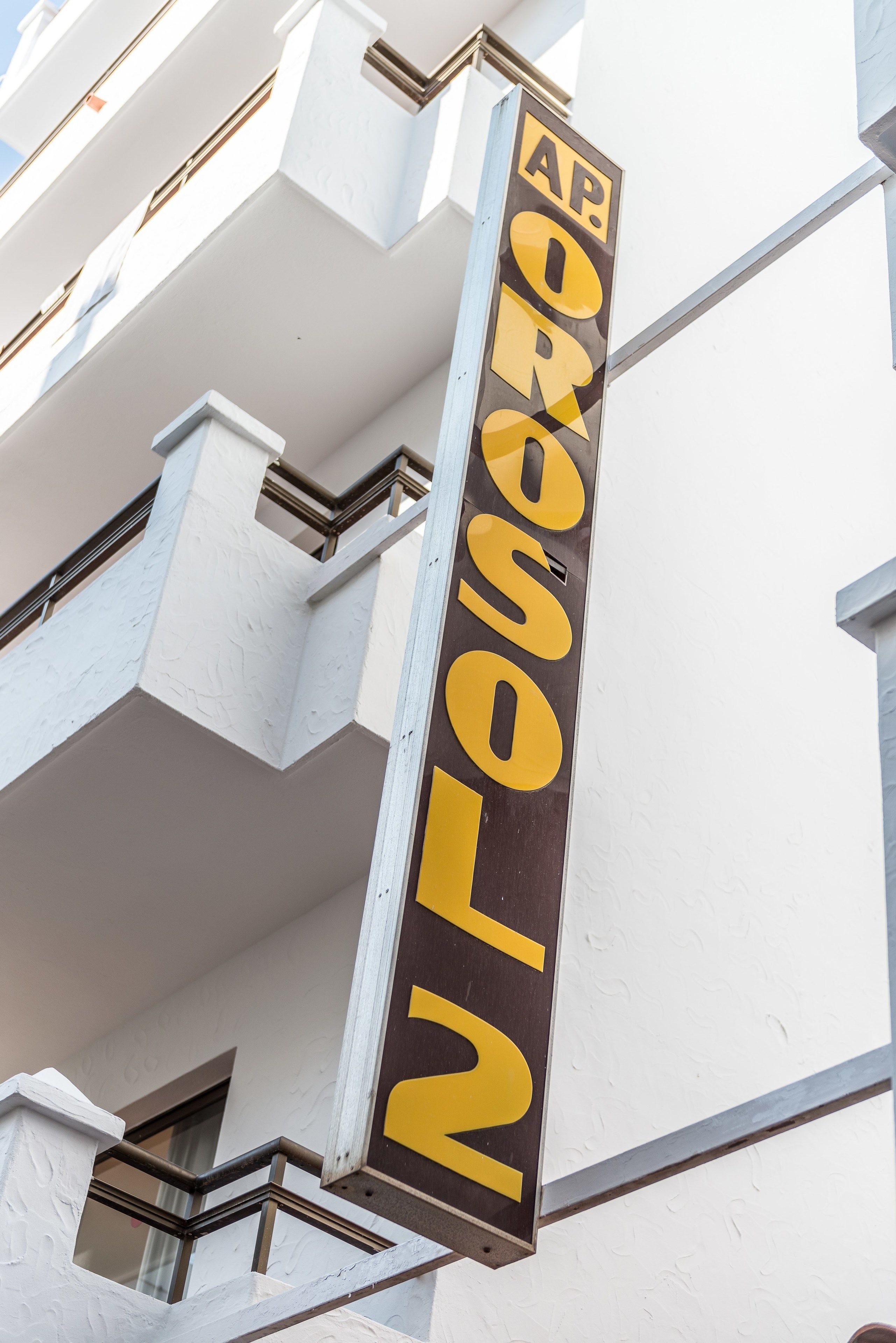 A vertical sign with the letters "AP" at the top and "N" at the bottom, mounted on a building facade.