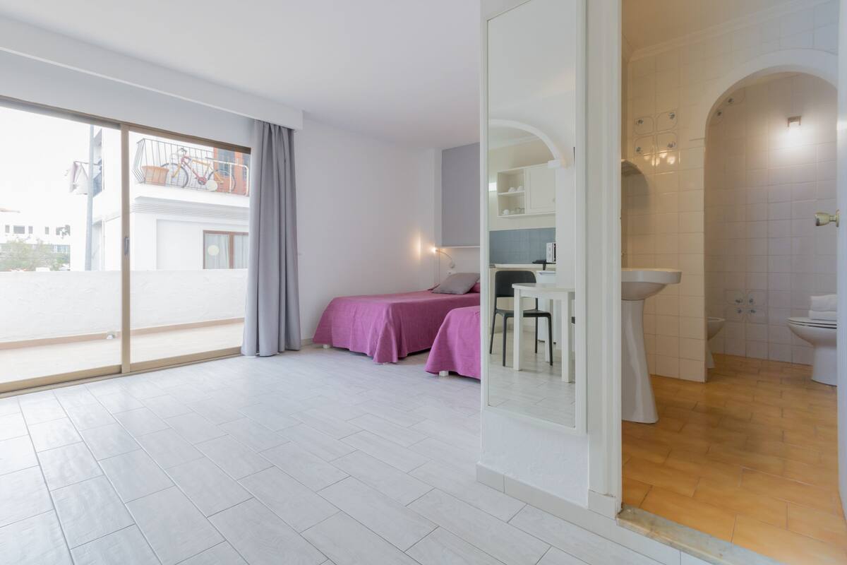Una habitación de hotel moderna con balcón, baño privado y zona de comedor.