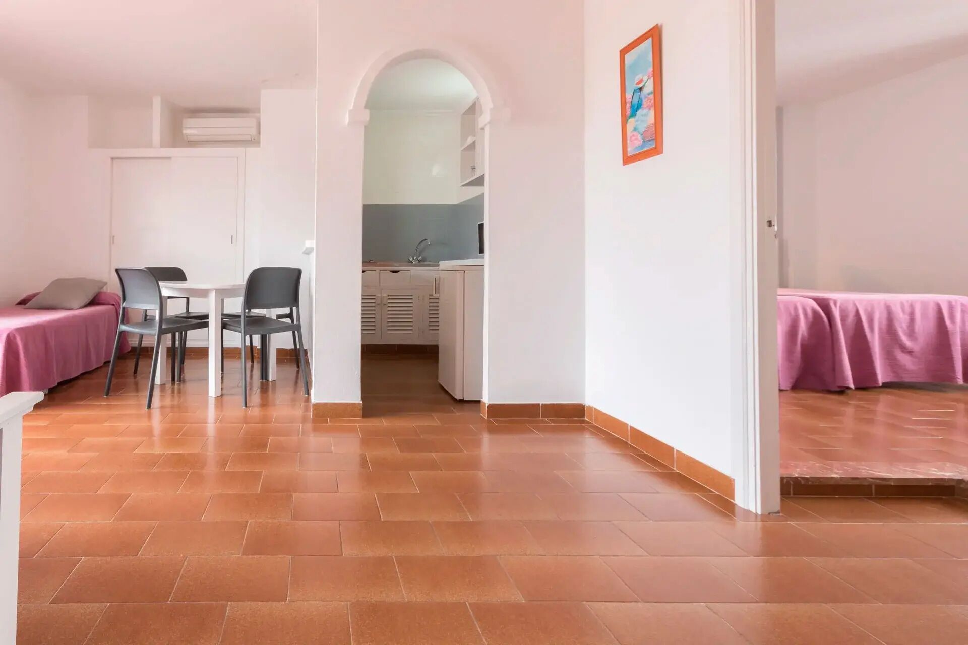 Un espacio habitable compacto con comedor, kitchenette y dormitorio.