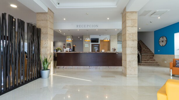 A modern reception area with a marble counter, a reception desk, and a staircase leading to upper floors.