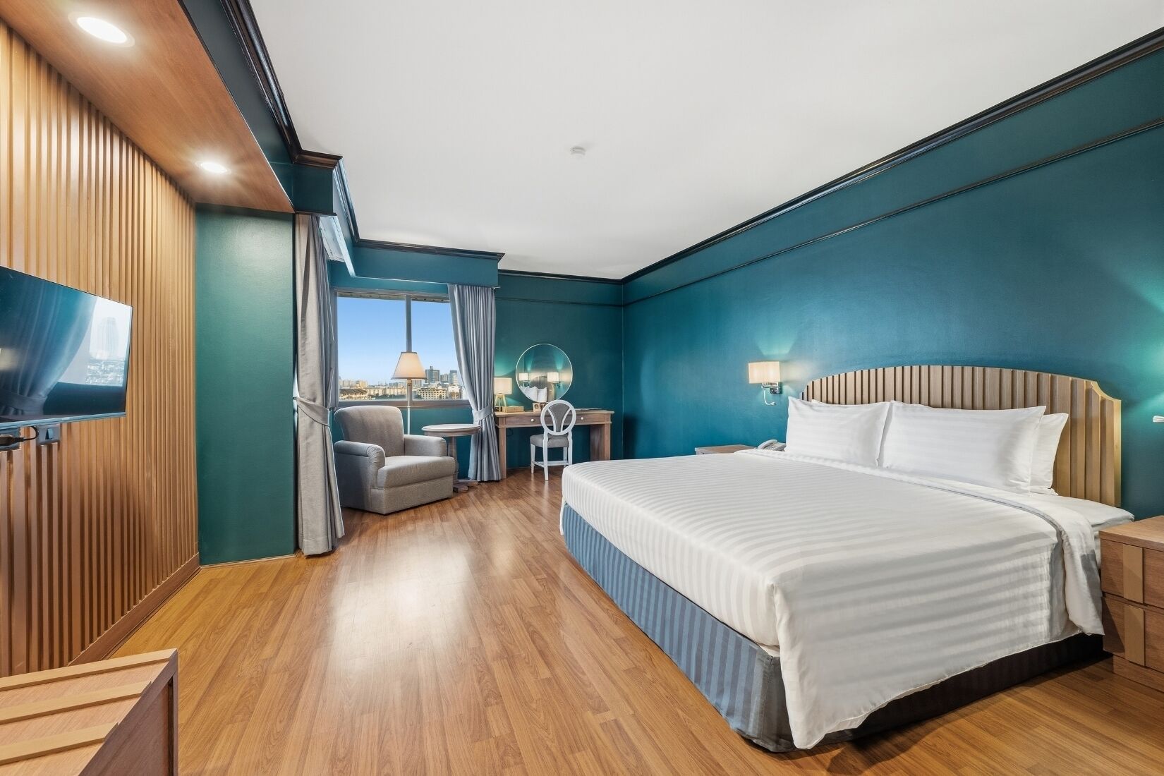 Een moderne hotelkamer met een groot bed, een bureau, een stoel, een televisie en uitzicht op de stad.