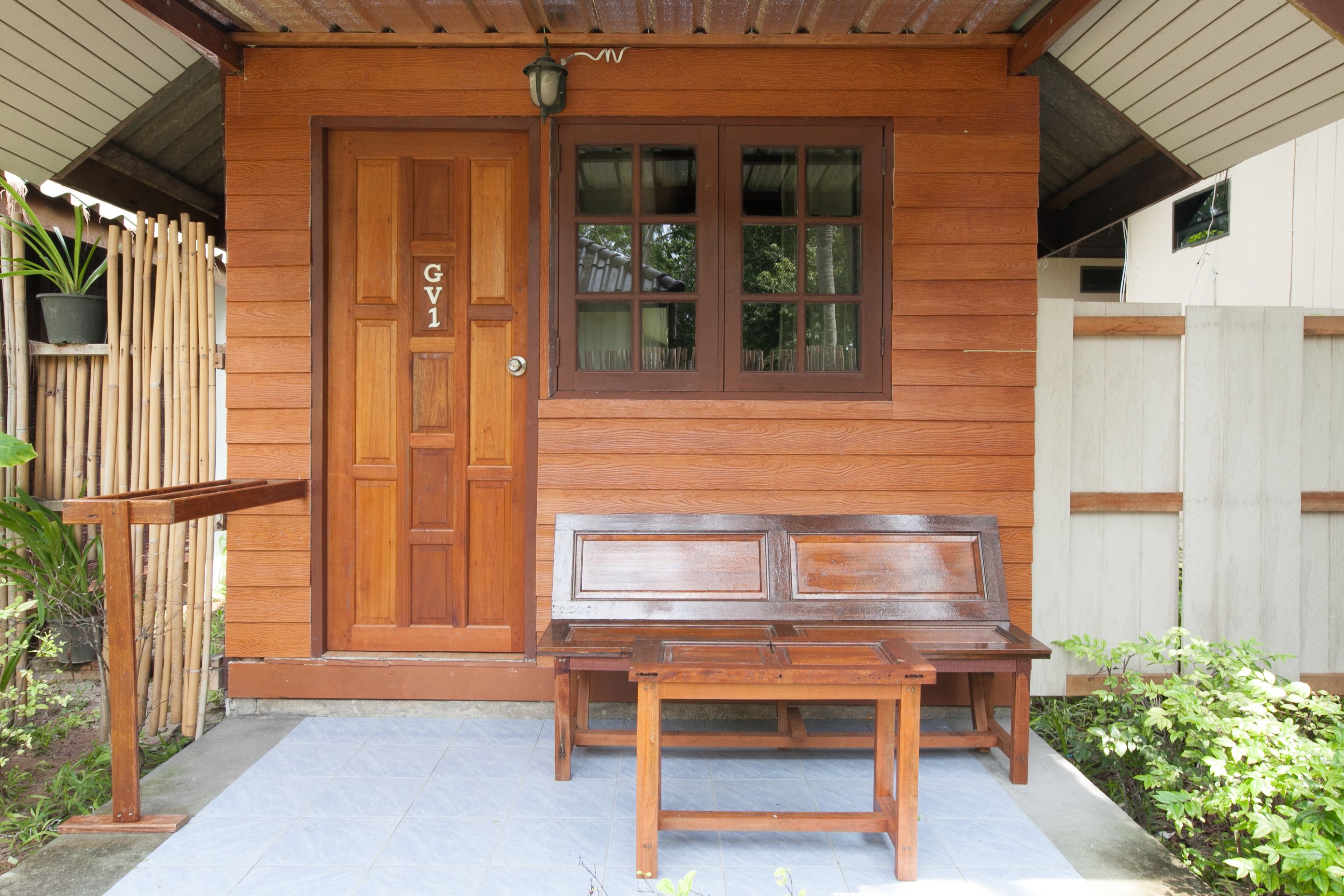 A wooden building with a door labeled "GV1" and a bench in front.
