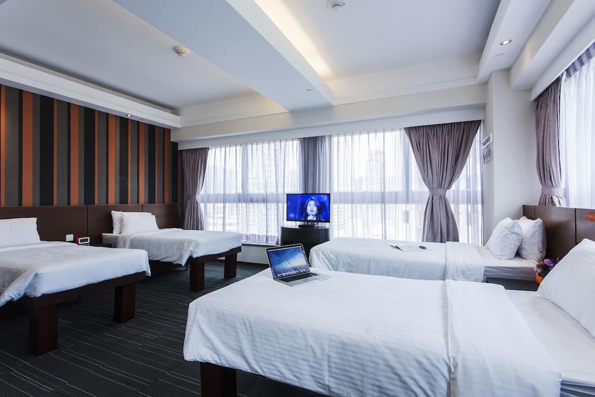 A hotel room with two beds, a TV, and a laptop on one bed.