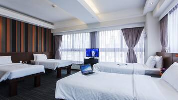 Una habitación de hotel con dos camas, un televisor y una computadora portátil sobre una de ellas.