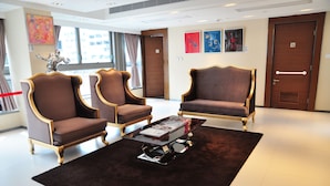 A hotel lobby with three armchairs, a coffee table, and a large window. - Le Prabelle Hotel (Kowloon)