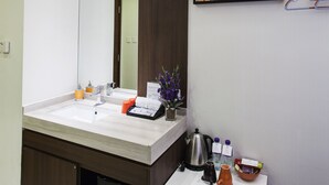 A modern bathroom with a large mirror, a sink, and a countertop with toiletries. - Le Prabelle Hotel (Kowloon)