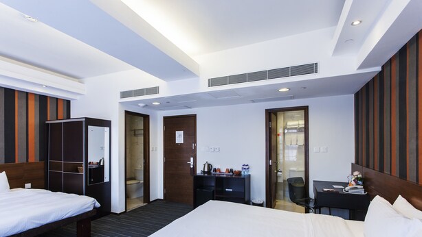 A hotel room with two beds, a desk, a chair, a wardrobe, and a bathroom. - Le Prabelle Hotel (Kowloon)